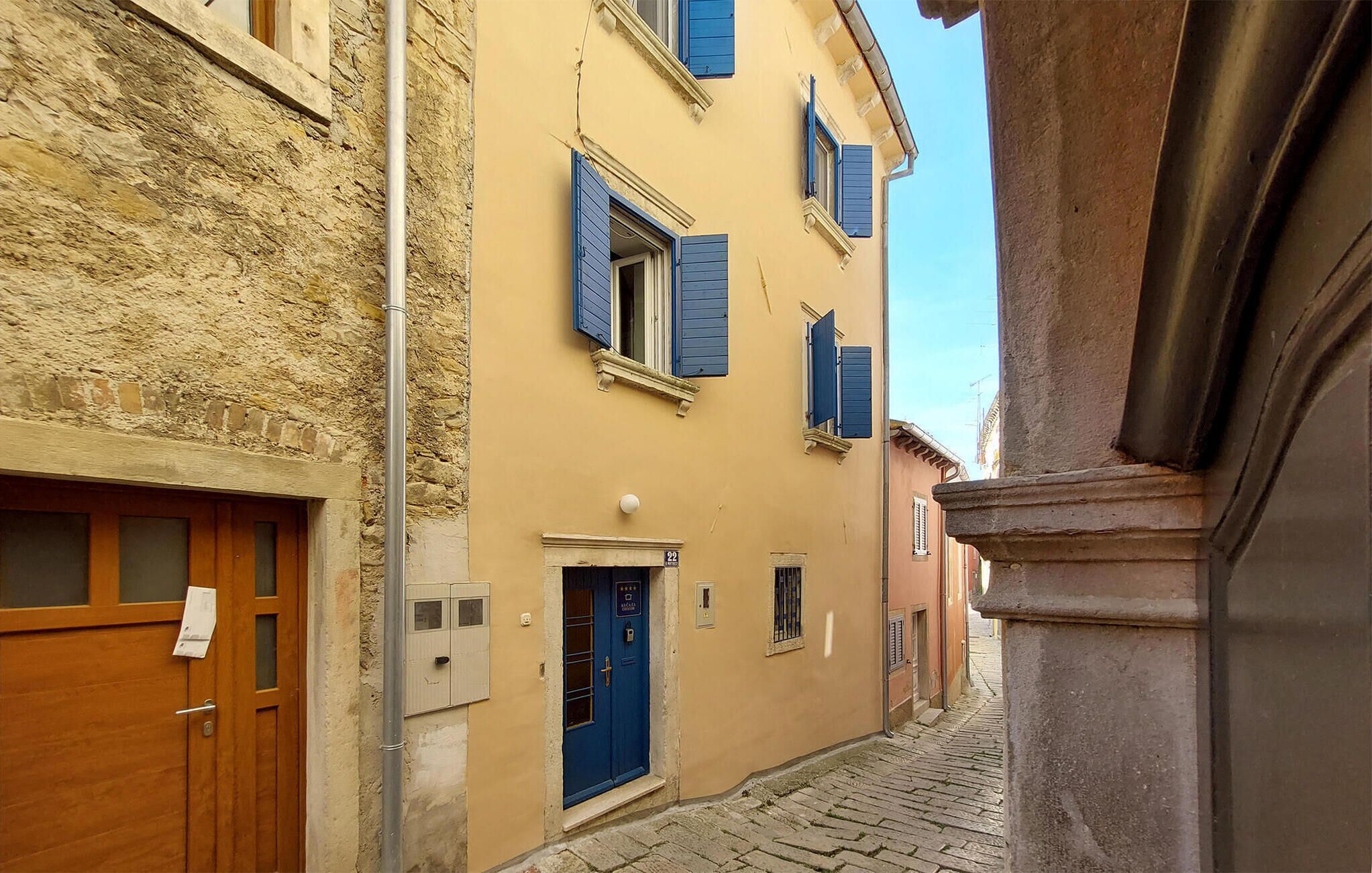 A narrow street with buildings featuring stone facades and wooden doors.