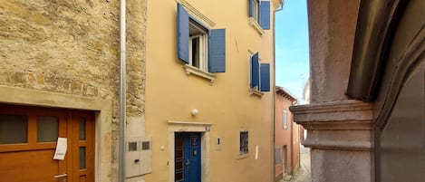 A narrow street with buildings featuring stone facades and wooden doors.