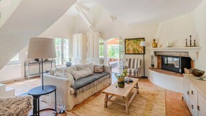 A spacious living room with a sofa, coffee table, and fireplace. There is a dining area with a table and chairs, and a view of the outdoors through large windows. - Awesome home in Carcès (Carcès)