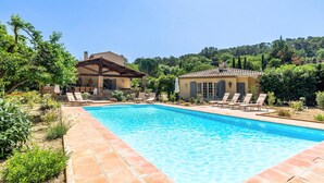 A swimming pool with lounge chairs, a stone patio, and a house with a tiled roof. - Awesome home in Carcès (Carcès)