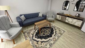 A modern living room with a sofa, armchair, coffee table, and a console table with decorative items. - Forbes Butik Otel (Izmir)