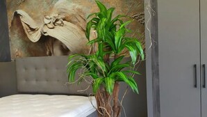 A bedroom with a bed, a large mural on the wall, and a potted plant. - Forbes Butik Otel (Izmir)