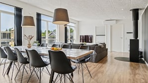 Een moderne eetruimte met een grote tafel, zwarte stoelen en hanglampen.