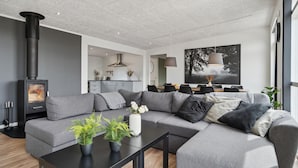 Een moderne woonkamer met een hoekbank, een zwarte salontafel en een open haard.