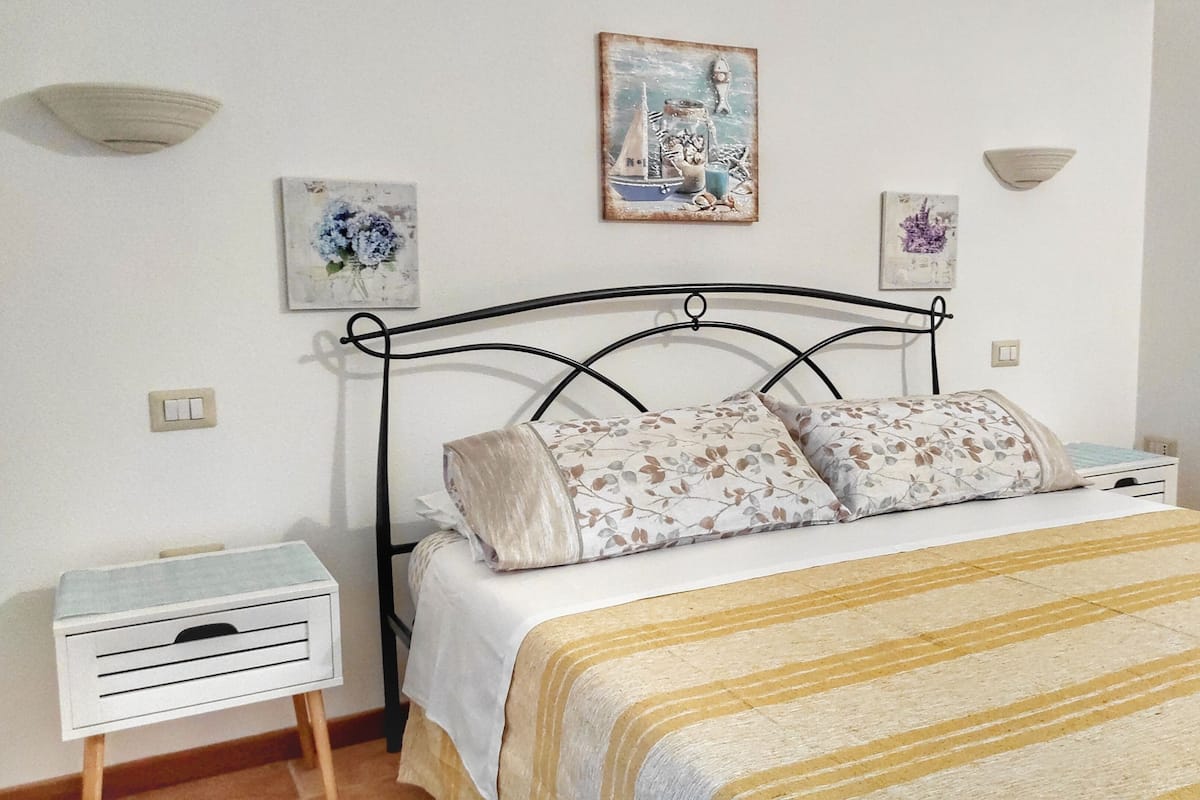 A bedroom with a bed, a nightstand, a bedside table, and wall-mounted light fixtures.