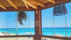 A wooden deck with a table and chairs overlooking a beach. - STELLA DORADA VACANZE BEDROOMS (Castiadas)