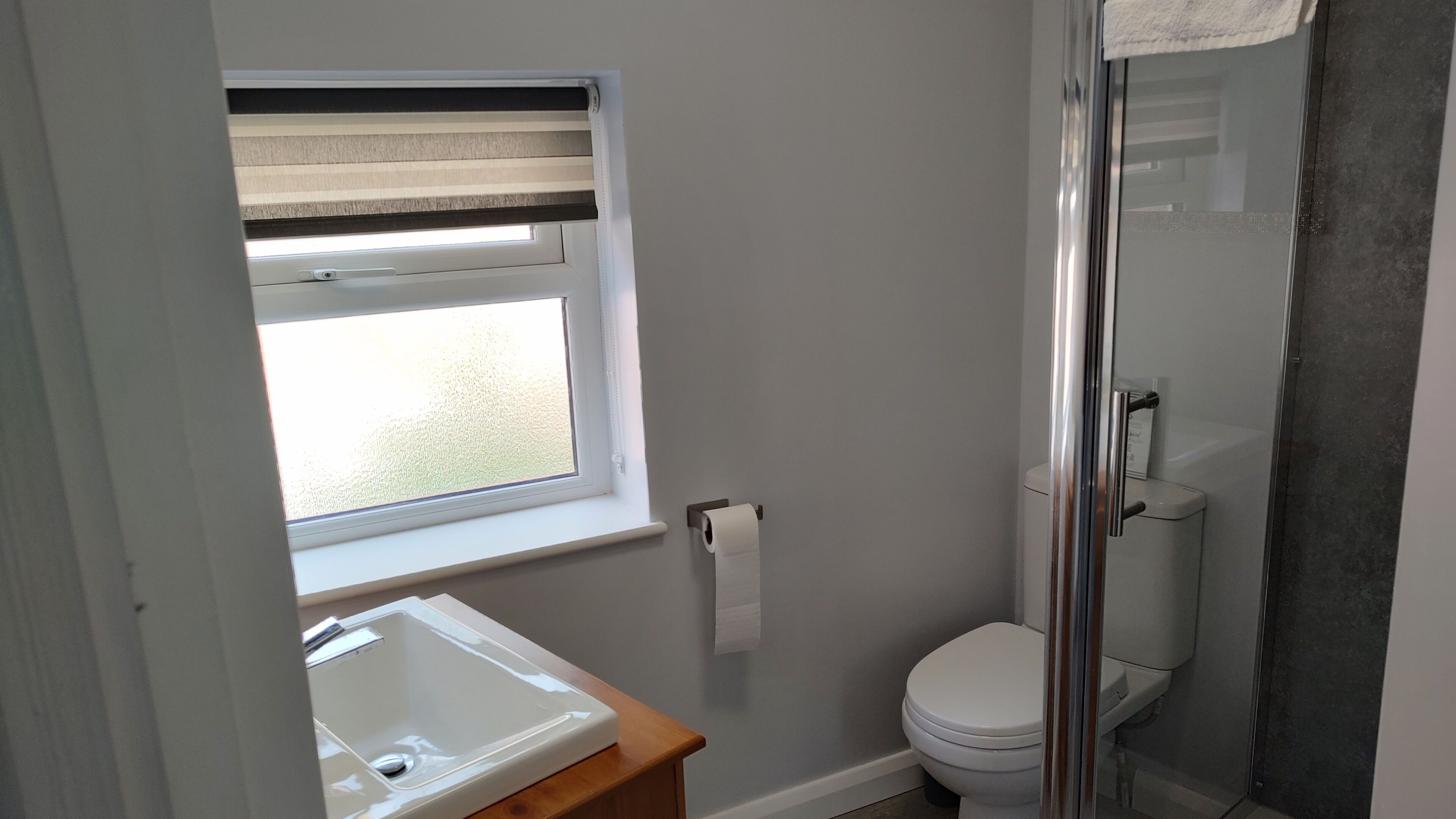 A small bathroom with a window, a toilet, and a sink.