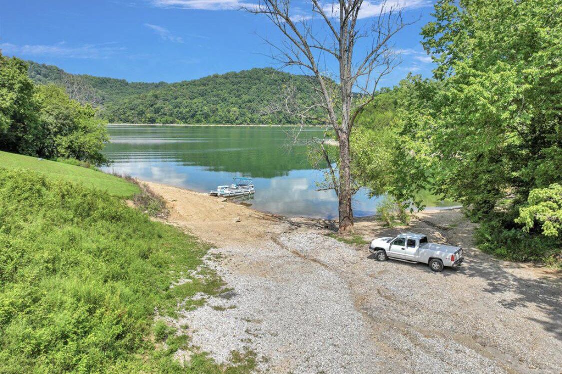 A gravel path leading to a lake with a boat docked on the shore.