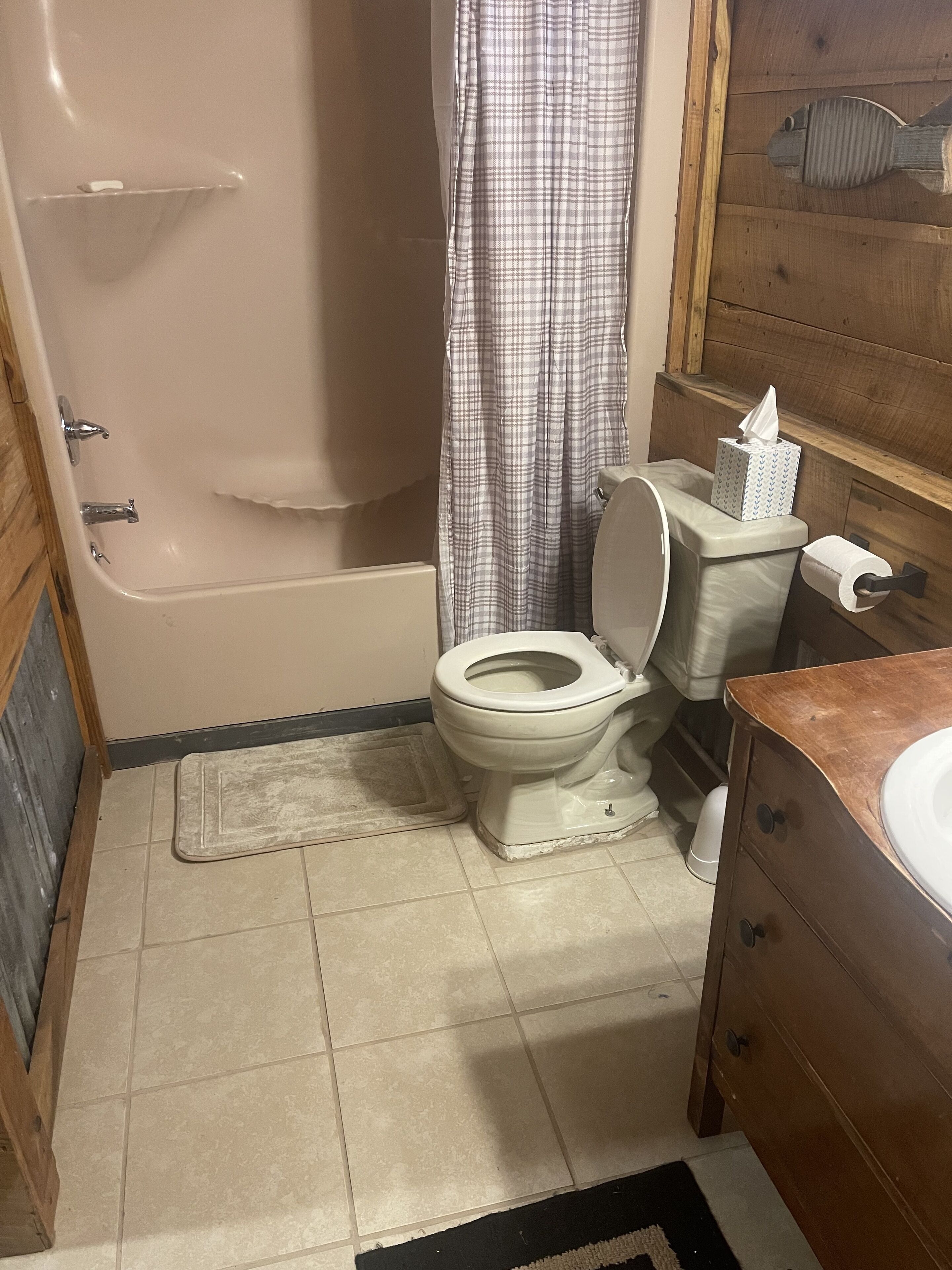 Ein Badezimmer mit Toilette, einer Badewanne, einer Duschkabine, einem Taschentuchbehälter und einem Waschbecken.