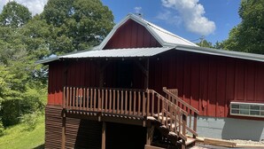 A red barn with a wooden porch and a metal roof. - Mine Lick Creek Resort 128 (Baxter)