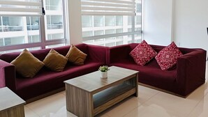 Un salon moderne avec deux canapés rouges, une table basse en bois et de grandes fenêtres équipées de stores.