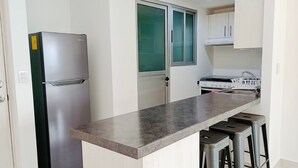Une cuisine moderne dotée d’un réfrigérateur en acier inoxydable, d’un four encastré et d’un plan de travail en granit.