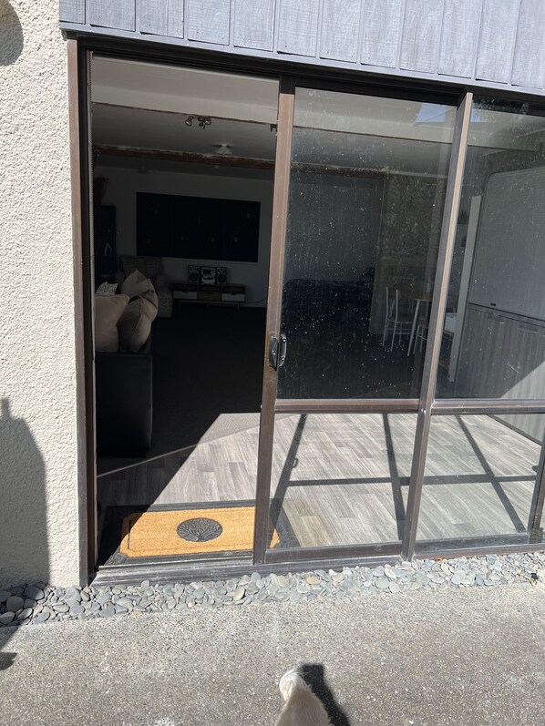 A sliding glass door leading to a living area with a sofa, a coffee table, and a television.