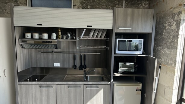 A compact kitchen with a built-in microwave, a sink, and a small refrigerator. - Cosy comfortable unit with city views (Napier)
