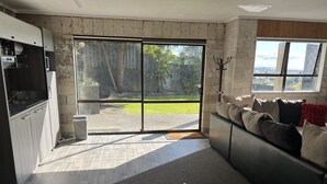 A modern kitchen with a sliding glass door leading to a backyard. - Cosy comfortable unit with city views (Napier)