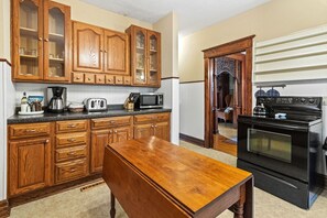 A kitchen with wooden cabinets, a countertop with appliances, and a dining table.