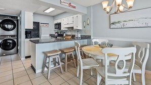 Een keuken met een centraal eiland, witte kasten, en een bord met de tekst 'Ga maar in de Oceaan springen'.