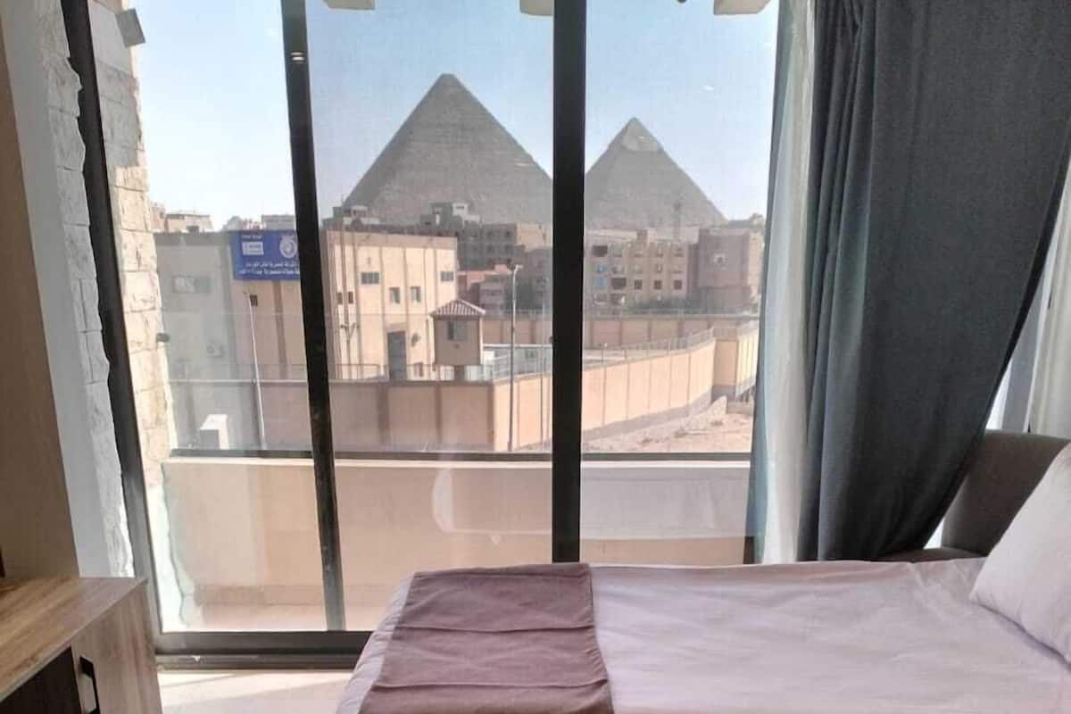 Habitación de hotel con dos camas, vista a la pirámide y al paisaje urbano.