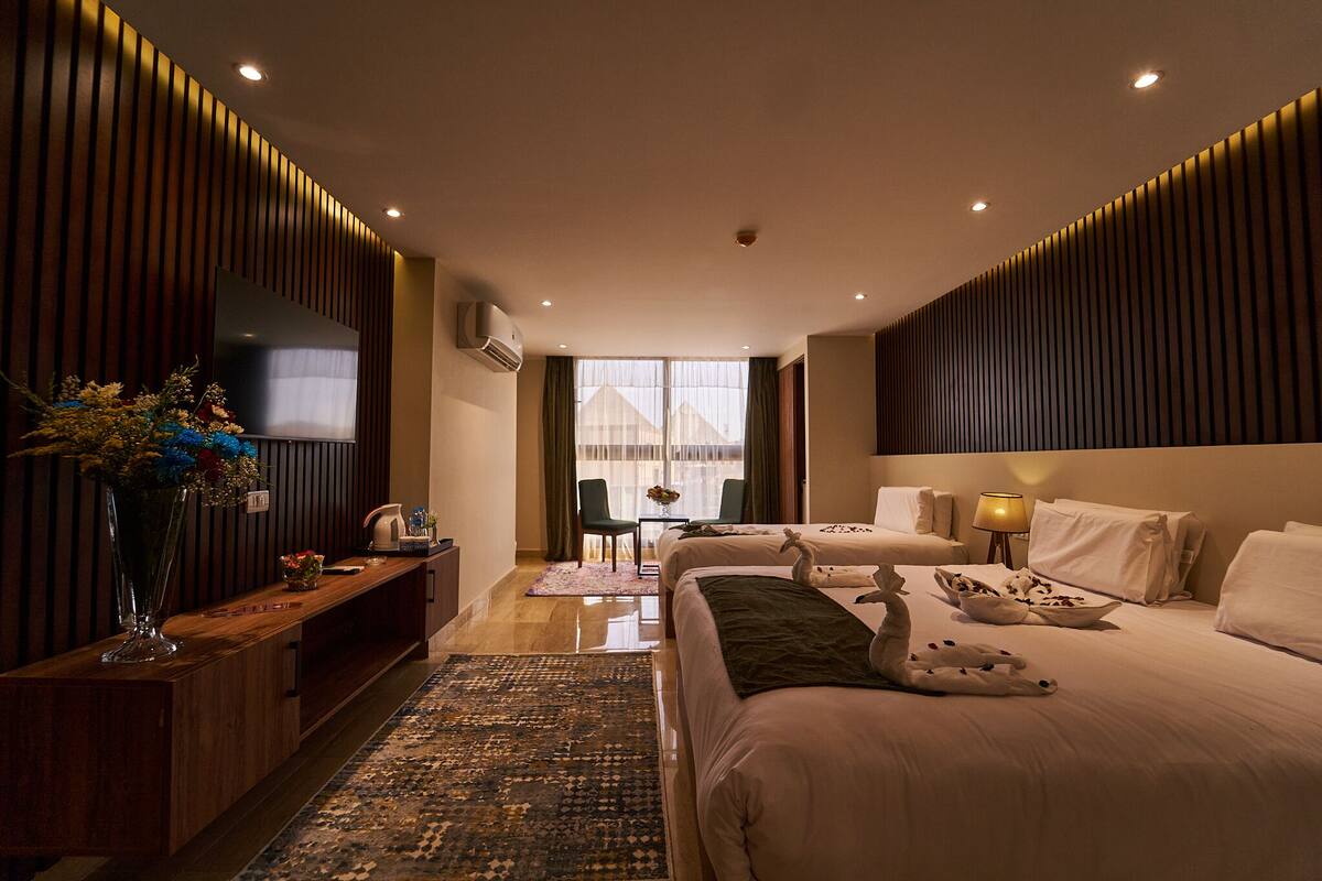 Una habitación de hotel moderna con una cama grande, televisión, escritorio y vistas al exterior.