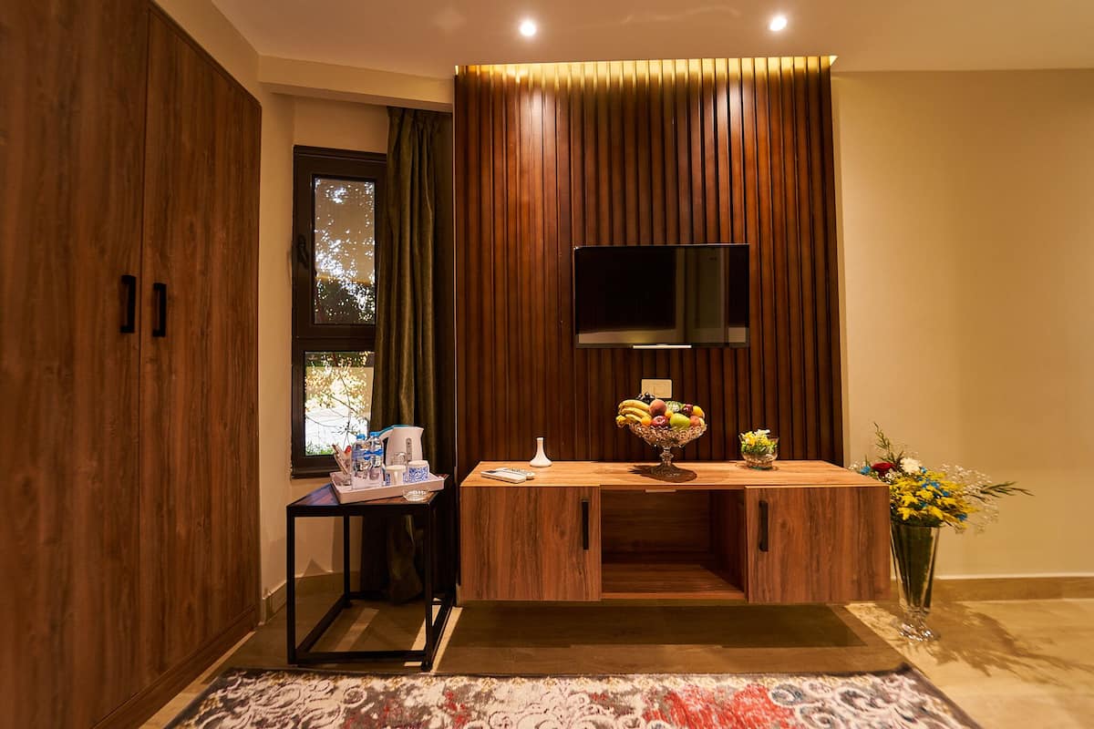 Una habitación moderna con un escritorio de madera, un televisor de pantalla plana y un jarrón con flores.