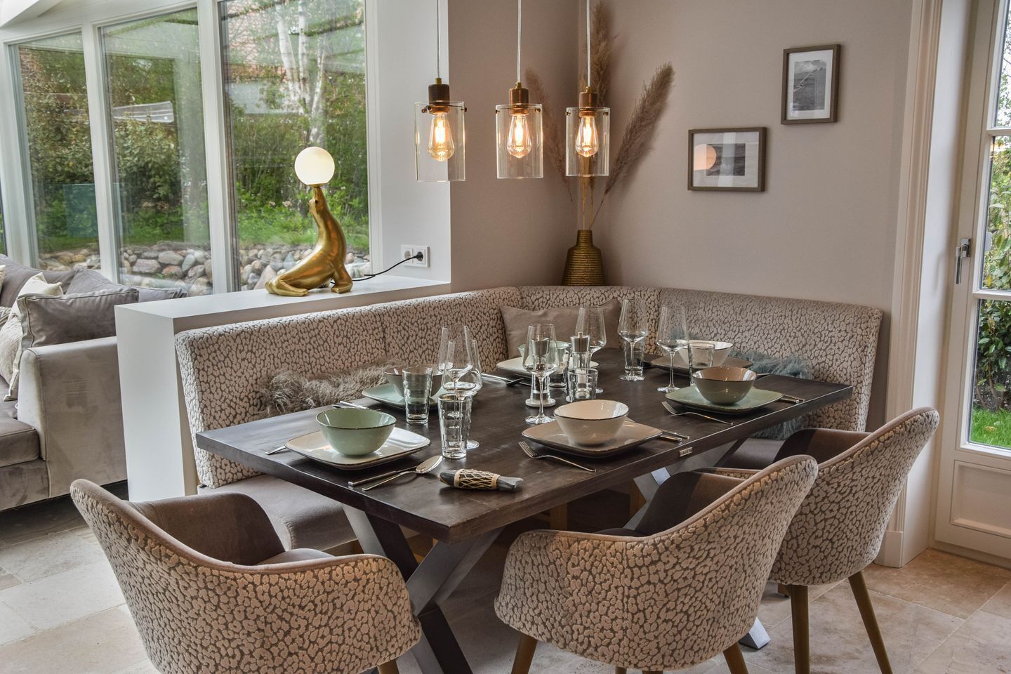 Un coin repas avec une table en verre dressée pour six personnes, entourée de chaises aux motifs variés.