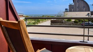A balcony with a view of the sea and a building with a curved roof. - Land in sight with sauna - The best thing about Sylt? The sea. (List)