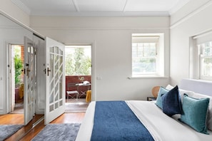 A bedroom with a bed, a window, and a balcony with a table and chairs.