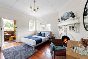 Un dormitorio con cama, chimenea, espejo y vistas al exterior.