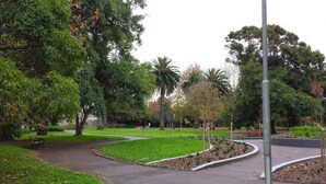 A park with a curved pathway, benches, and various trees. - The Meadow Gardens Oasis (St Kilda East)