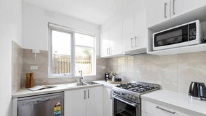 Una cocina moderna con gabinetes blancos, lavavajillas, estufa y microondas.
