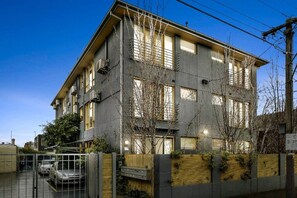 A multi-story building with a flat roof, large windows, and a gated entrance.