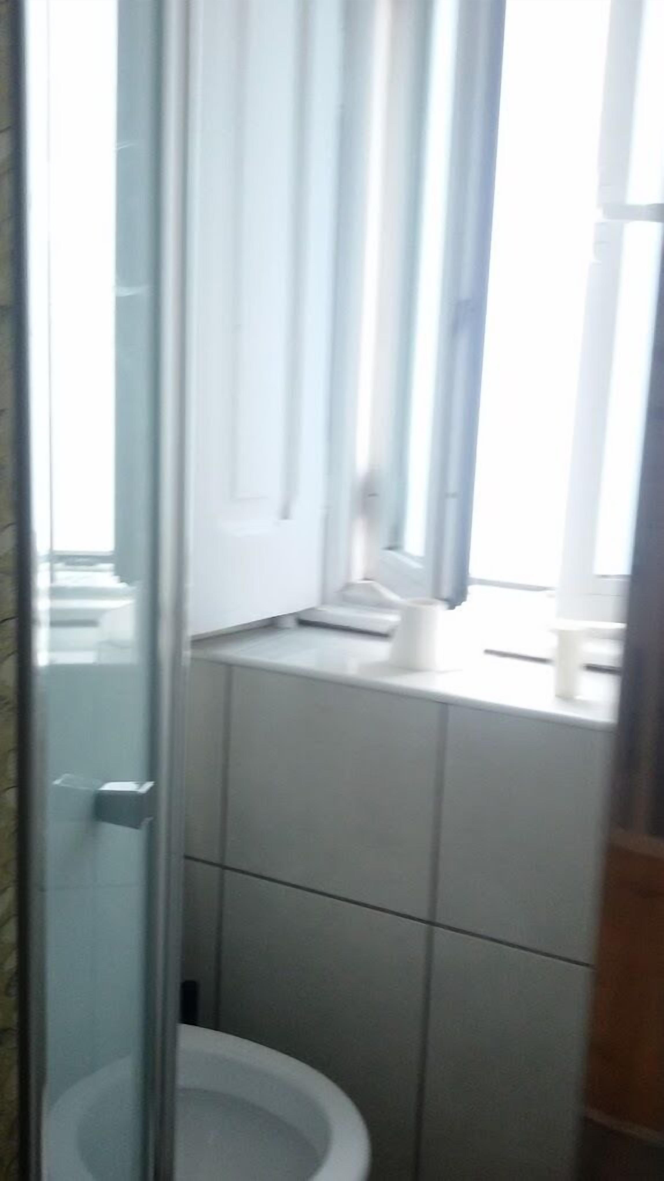 Un baño pequeño y estrecho con inodoro, lavamanos y ventana.
