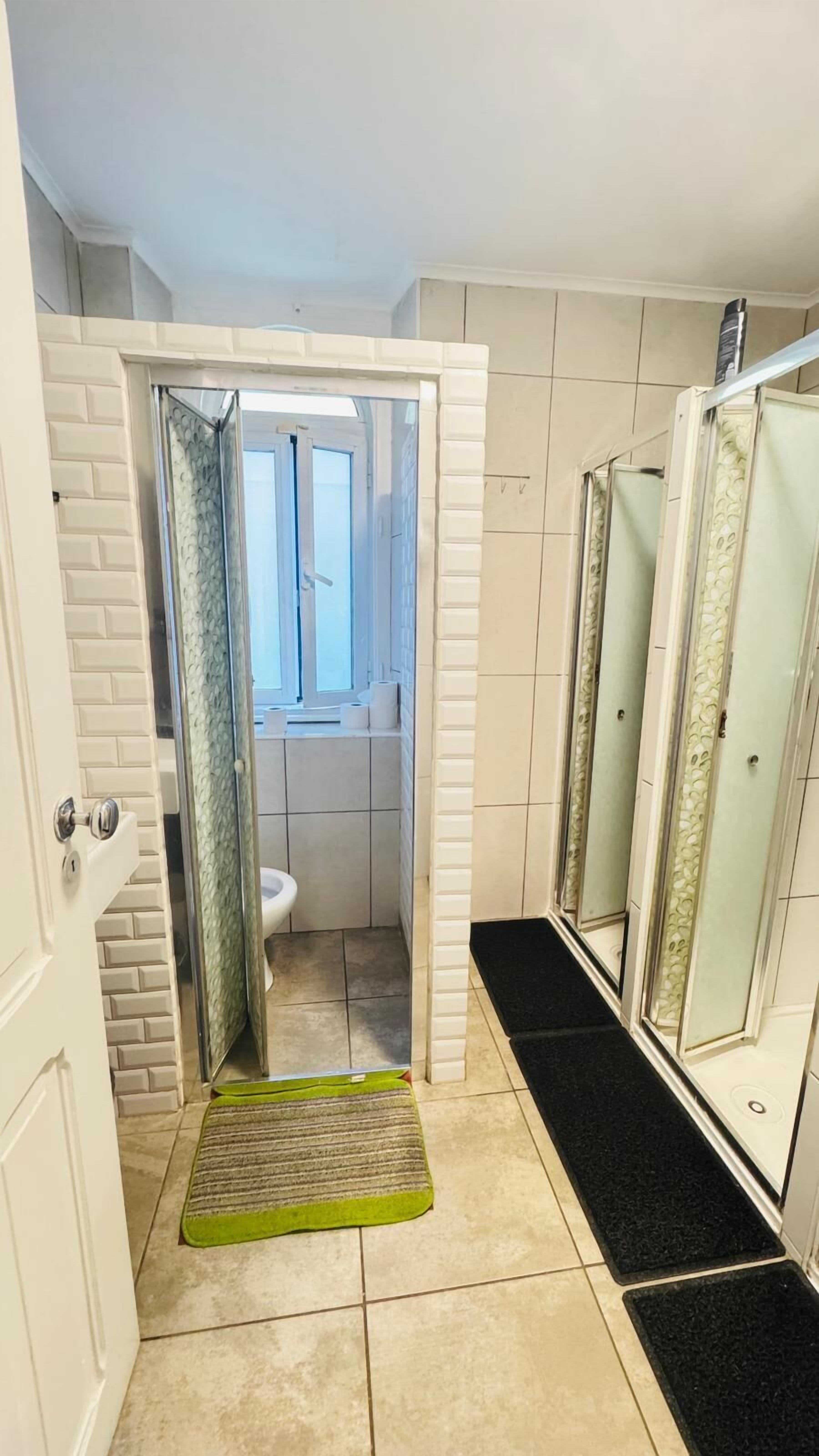 Un baño pequeño con zona de ducha, inodoro y lavabo.