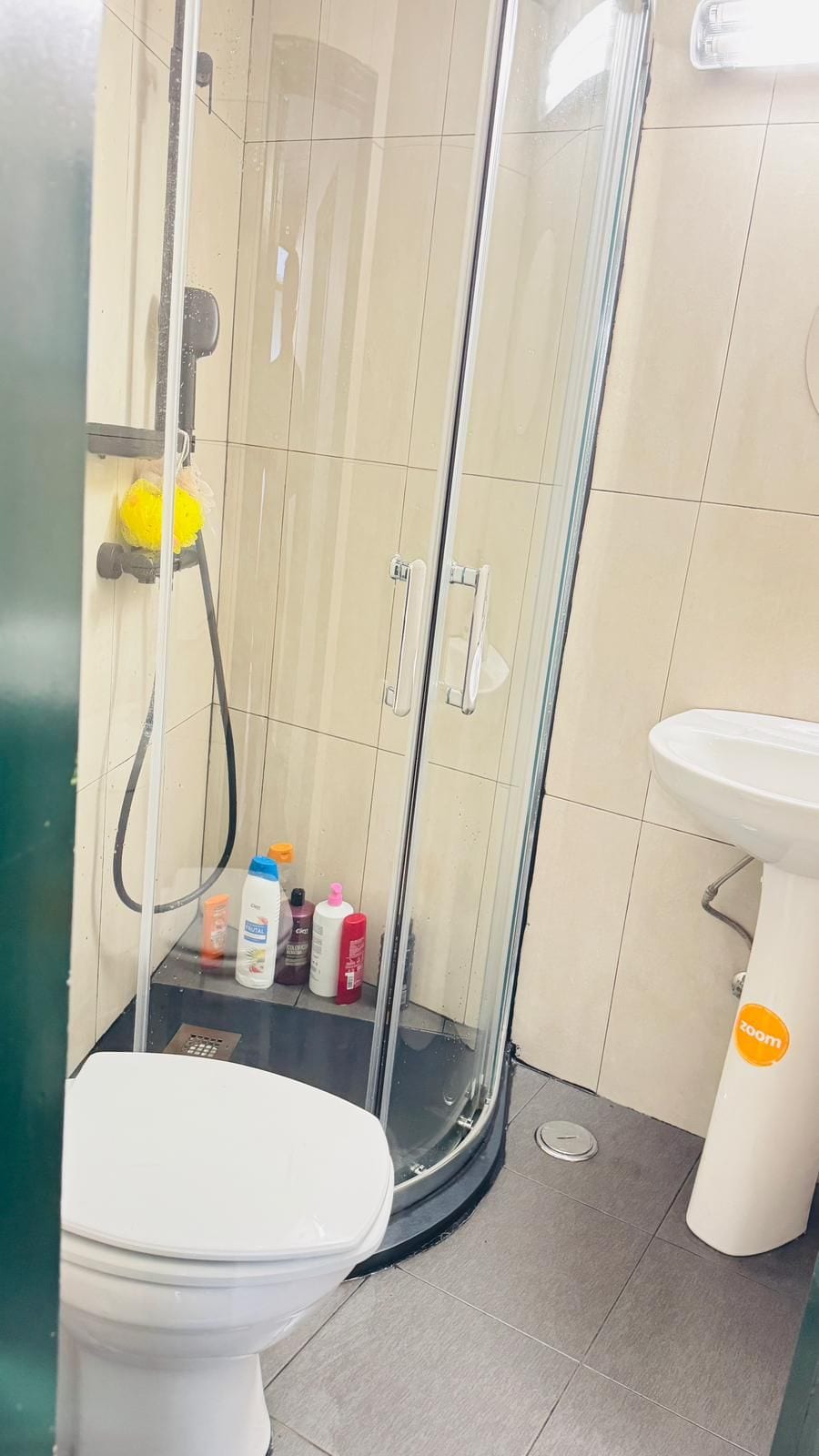 Un baño con cabina de ducha de vidrio, inodoro y lavamanos.