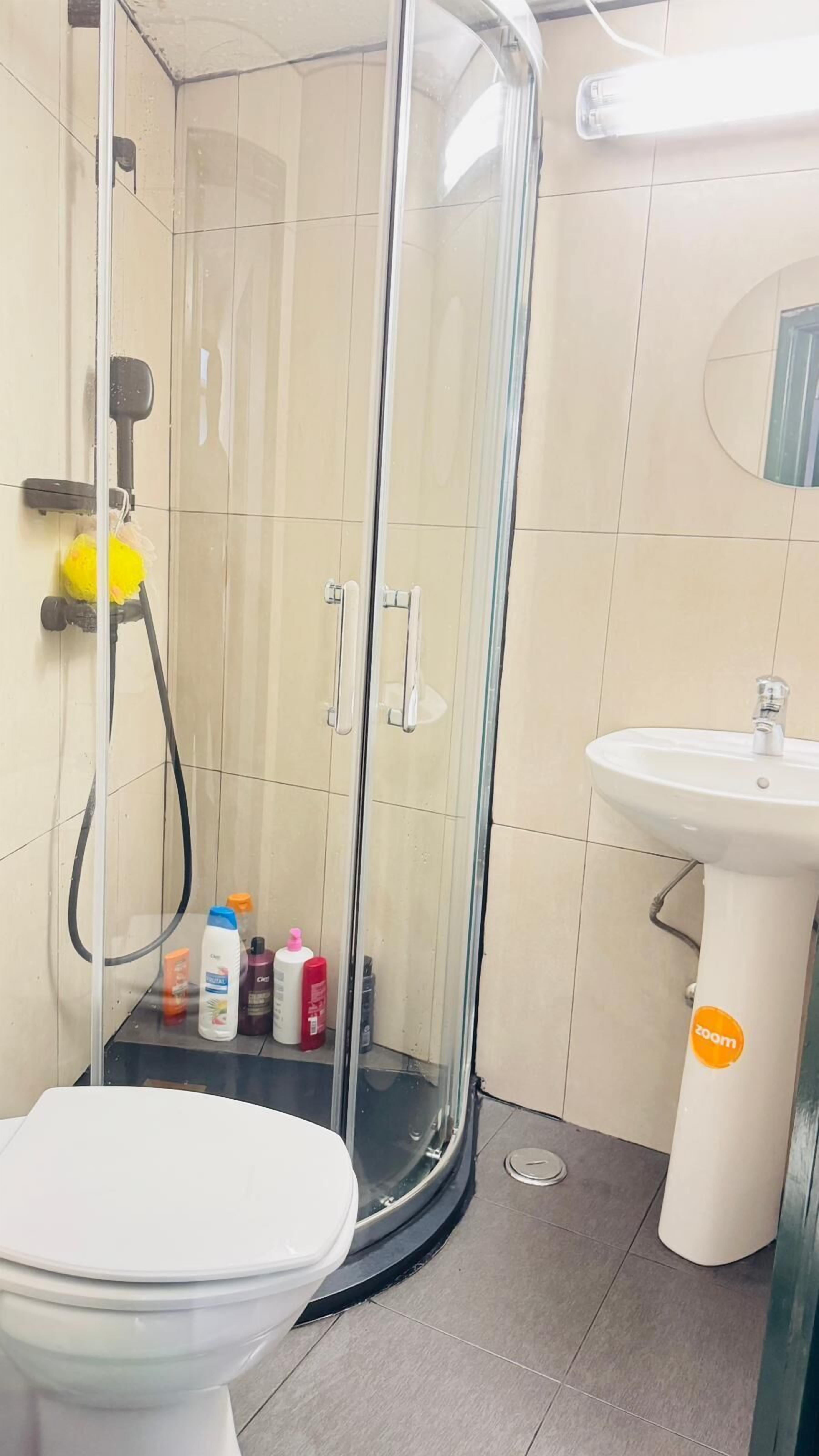 Et badeværelse med bruseniche, en hvid vask og et toilet.