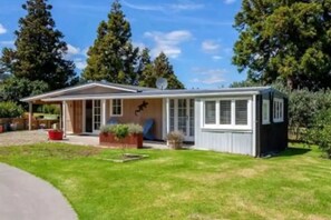 Une maison de plain-pied avec un porche à l’avant, un petit garage attenant et une pelouse bien entretenue.