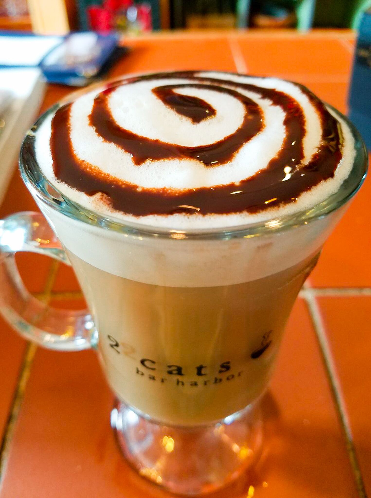 Una taza de vidrio con un diseño de arte latte en la superficie.