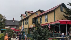 A building with a green porch and outdoor seating area. - Historic 2 Cats Inn (Bar Harbor)
