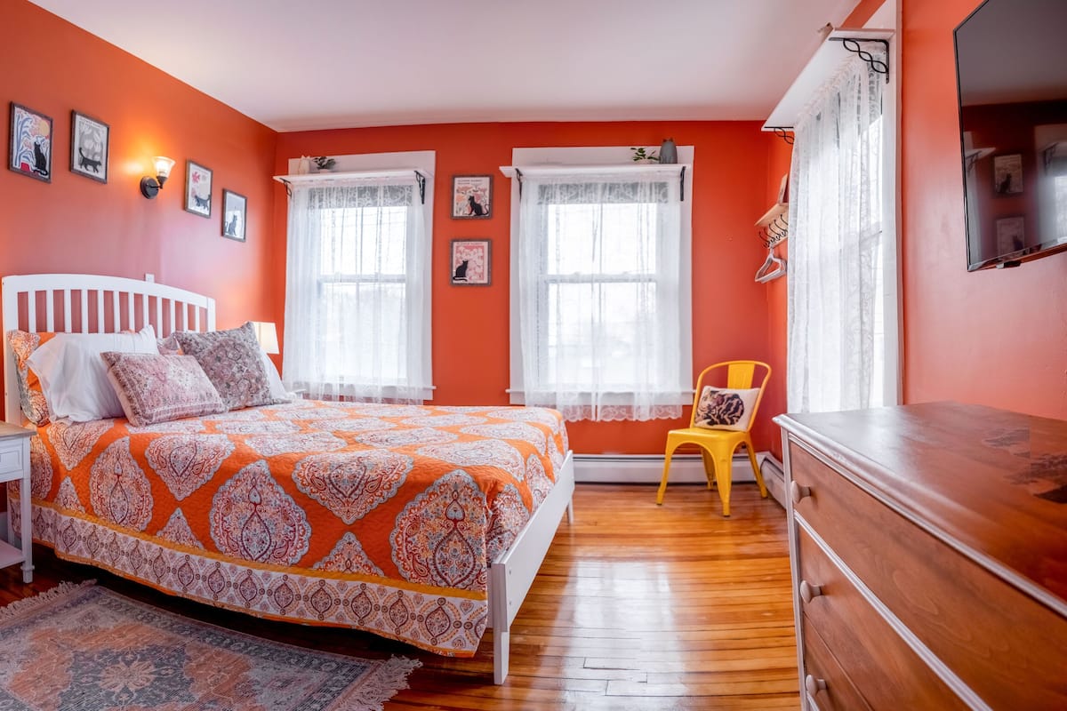 A bedroom with a bed, nightstand, dresser, and a chair.