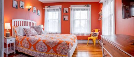 A bedroom with a bed, nightstand, dresser, and a chair.