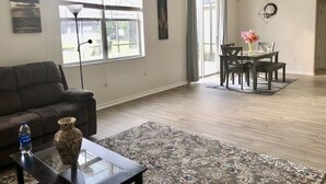 A spacious living room with a sofa, coffee table, and a dining area with chairs and a table. - Family house in Kissimmee. (Kissimmee)