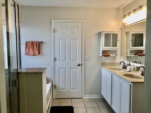 A compact bathroom with a white door, a sink with a mirror, and cabinets above the counter. - Family house in Kissimmee. (Kissimmee)