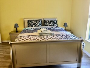 A bed with patterned bedding, two bedside lamps, and a window with a view. - Family house in Kissimmee. (Kissimmee)