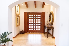 A hallway with a wooden door, a mirror, and framed pictures on the wall. - Guayllabamba Estate - Indoor Pool, Jacuzzi & Gym (Quito)
