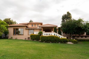 A two-story house with a tiled roof, a front porch, and a well-maintained lawn.