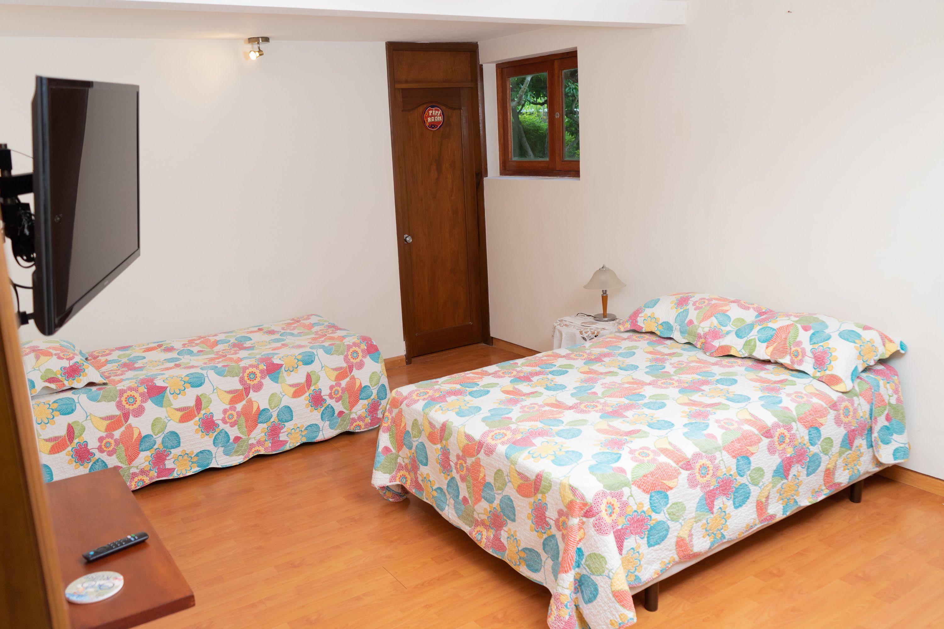 A bedroom with two beds, a TV, and a door marked 'Puff Room'.