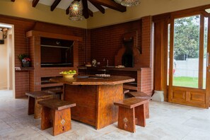 A brick-built outdoor kitchen with a central island, stools, and a pizza oven. - Guayllabamba Estate - Indoor Pool, Jacuzzi & Gym (Quito)