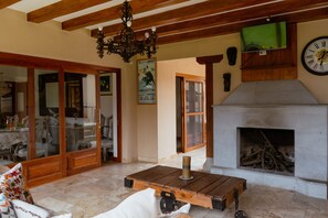 A cozy living room with a fireplace, wooden furniture, and a chandelier.