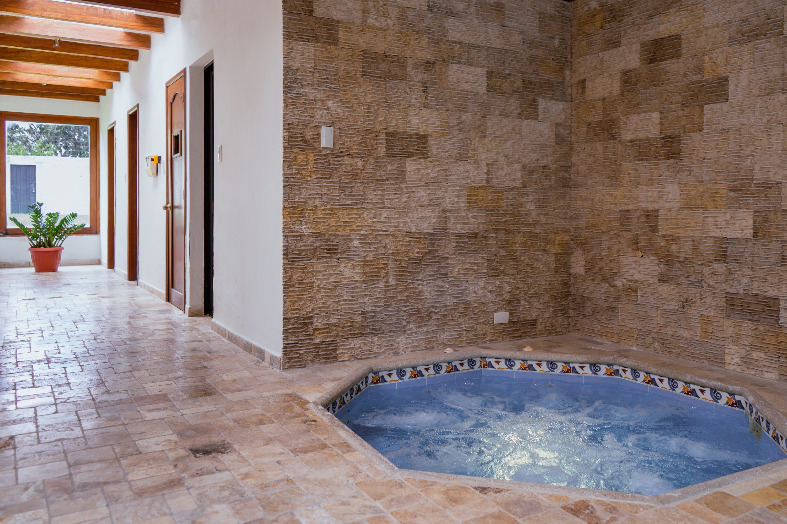 Un espace de bien-être avec un mur en pierre, un sol carrelé et un jacuzzi.