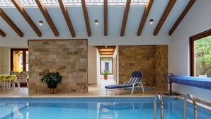 Une piscine intérieure offrant une vue dégagée sur le plafond, avec des murs en pierre et un fauteuil de relaxation.